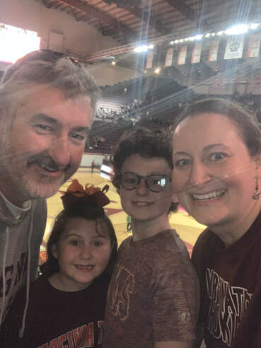 A family of four taking a selfie at a basketball game.