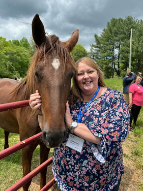 Rachel Hiatt posing next to a horse. She is holding the horse's head.
